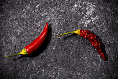 Top view of red fresh and dried small chili peppers on black stone background. concept of penis, potency and impotence, drugs for potency